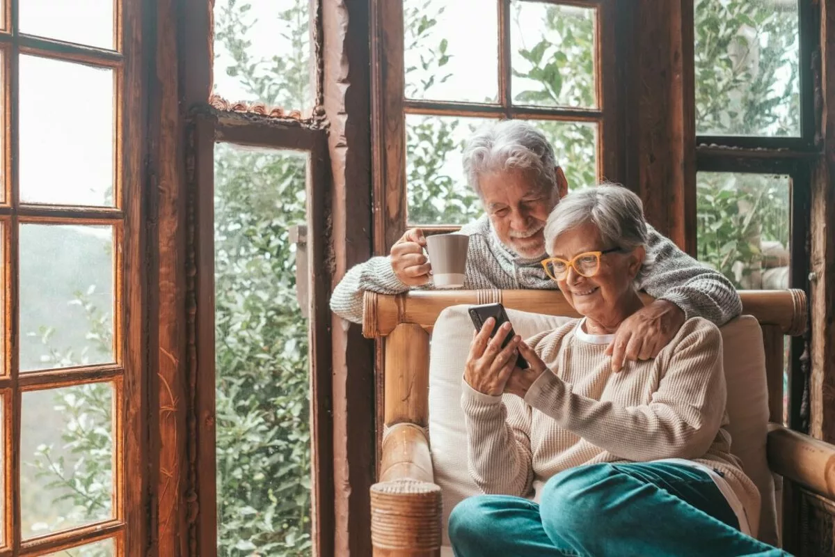 Couple of two old and mature people at home using phone together in sofa senior use smartphone.jpg