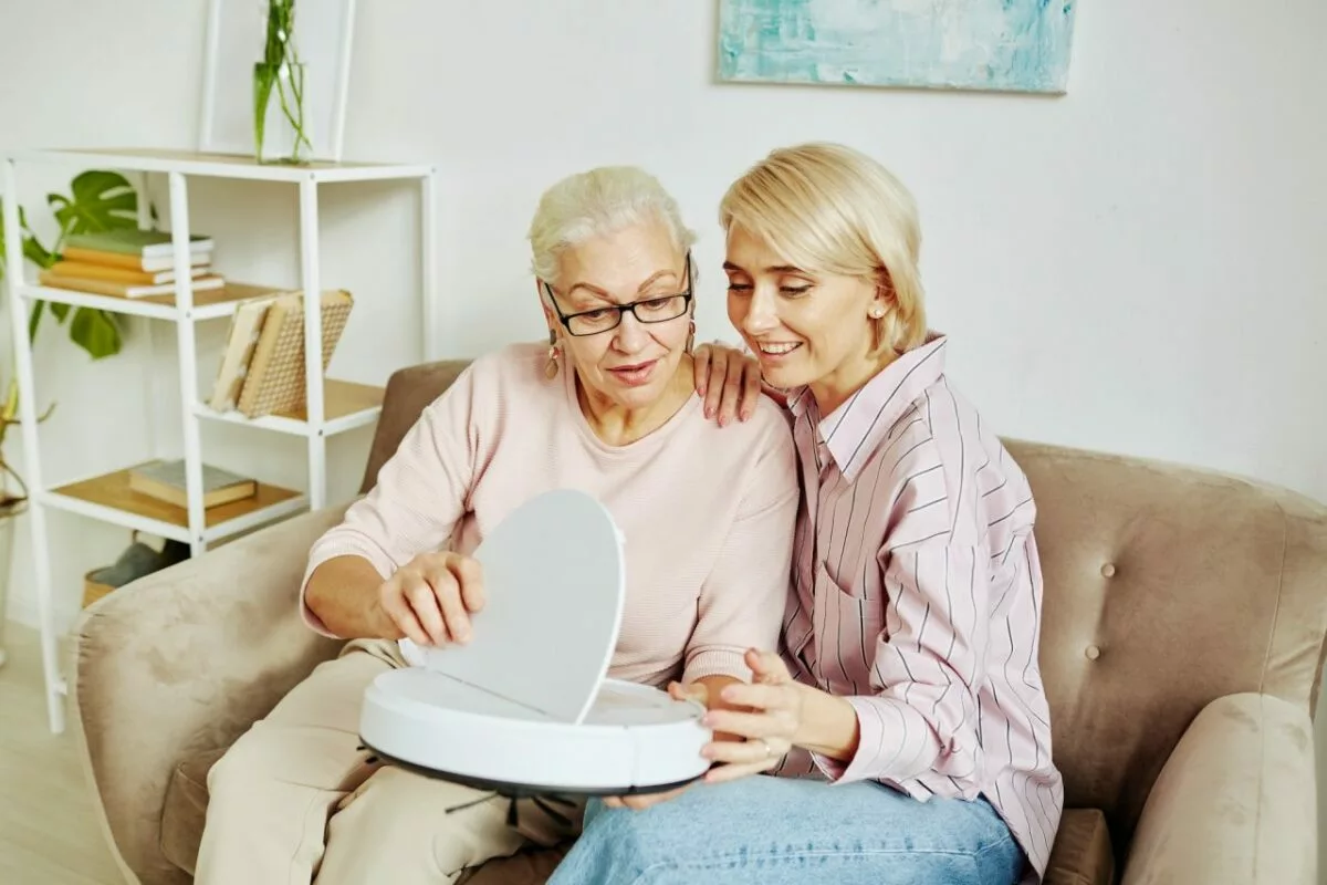 Senior woman holding smart vacuum cleaner.jpg